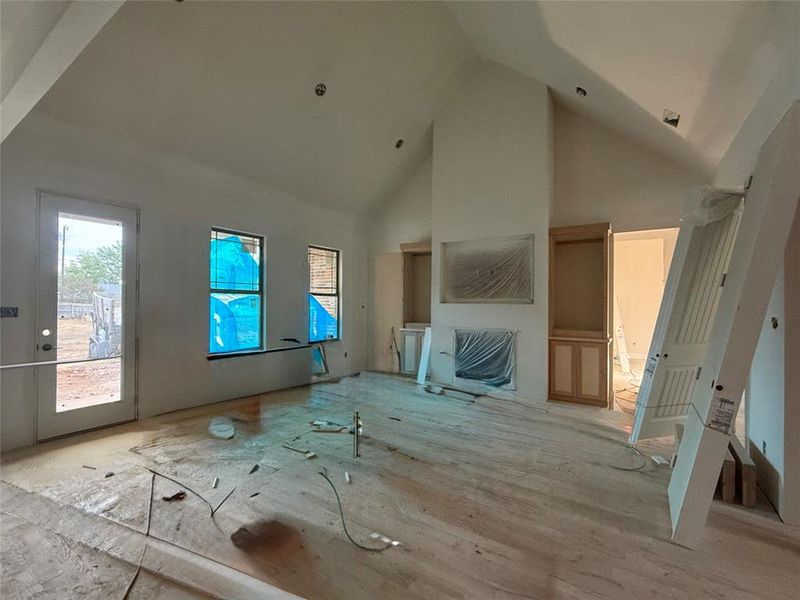 Unfurnished living room featuring light wood-type flooring and high vaulted ceiling