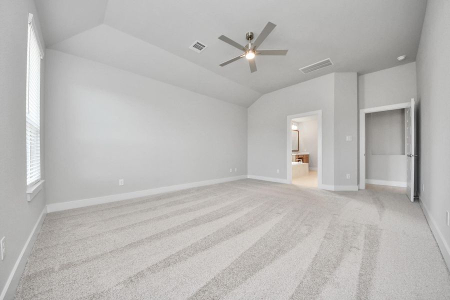 Escape and relax in the exquisite primary suite, a haven to unwind after a long day. The spacious room, located on first floor, boasts plush carpeting, soothing paint tones, high ceilings, and expansive windows adorned with privacy blinds.