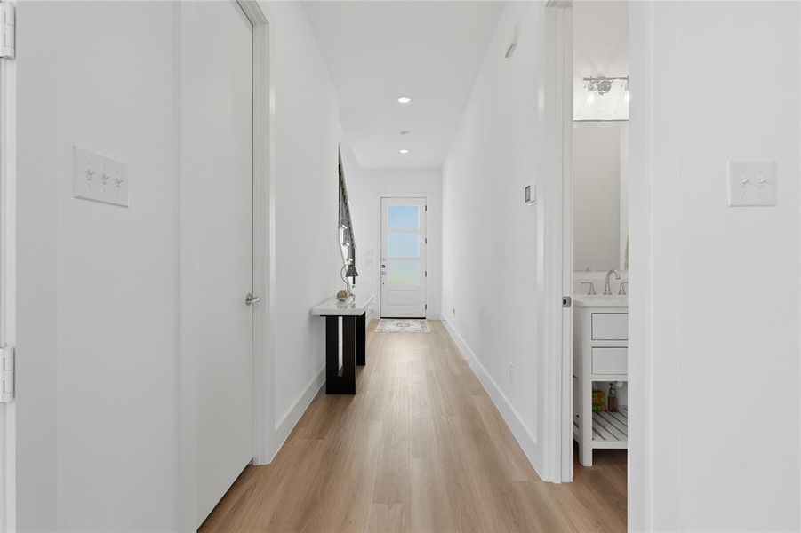 Hallway featuring wood-finish flooring, recessed lighting, and white baseboards