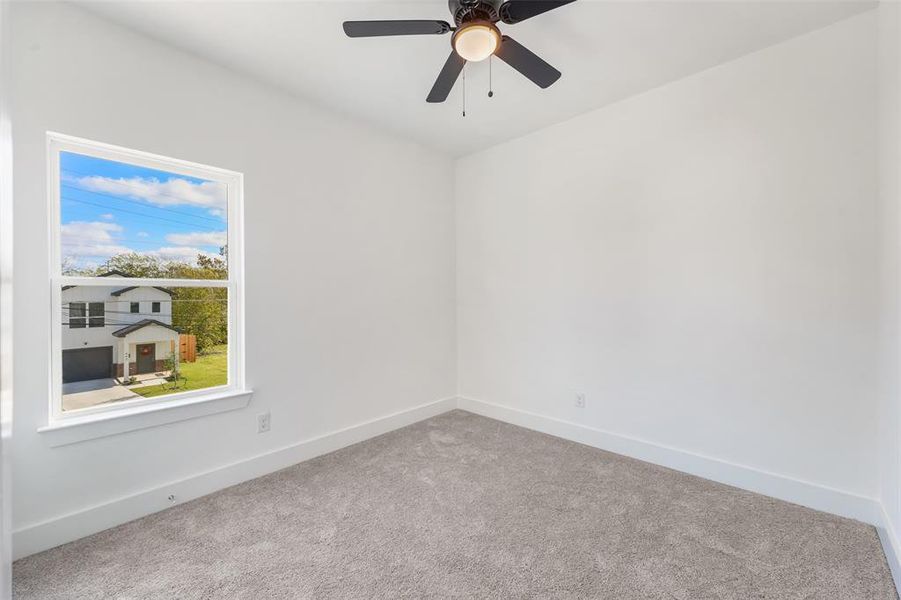 Carpeted spare room with baseboards and ceiling fan