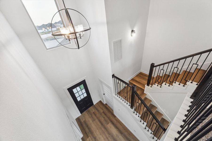 The elegant staircase with modern railing adds a touch of sophistication to the home's entryway. Natural light from the large window brightens the space, creating a welcoming atmosphere that sets the tone for the rest of the home.