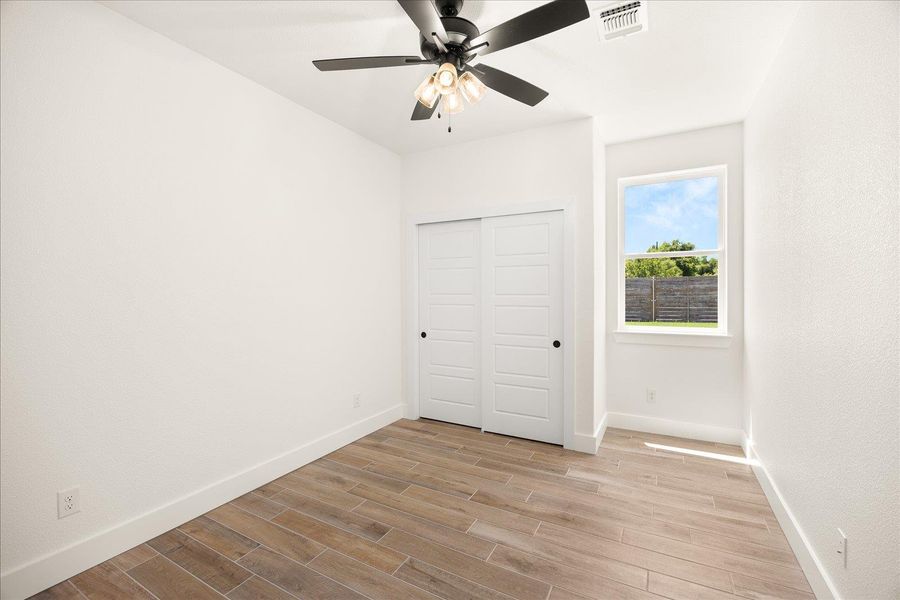A well-lit room showcases durable wood-look tile flooring and a bright window with a pleasant view.
