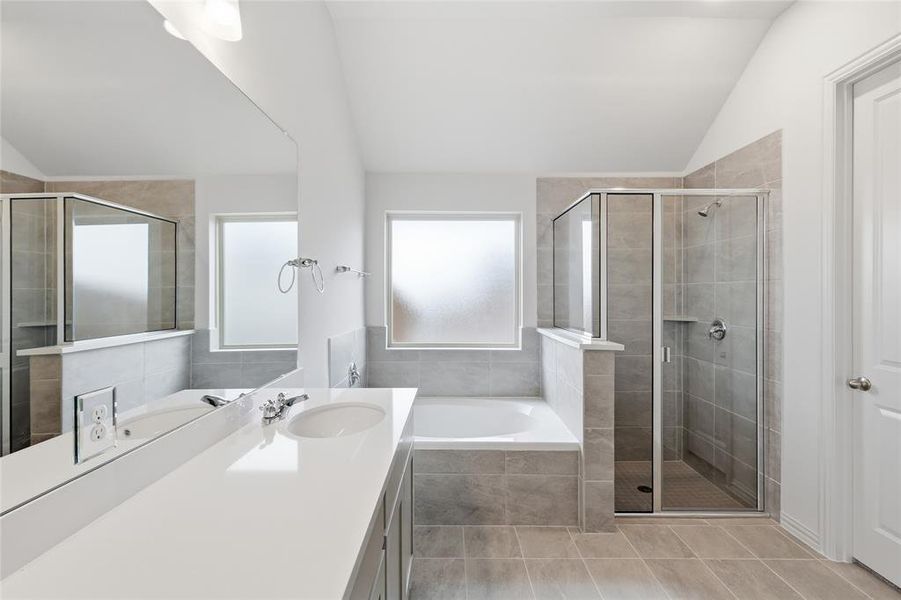 Spacious bathroom featuring a dual vanity with a white countertop, an integrated soaking tub, a separate glass-enclosed shower, and neutral tile flooring Spacious bathroom featuring a dual vanity with a white countertop, an integrated soaking tub, a separate glass-enclosed shower, and neutral tile flooring