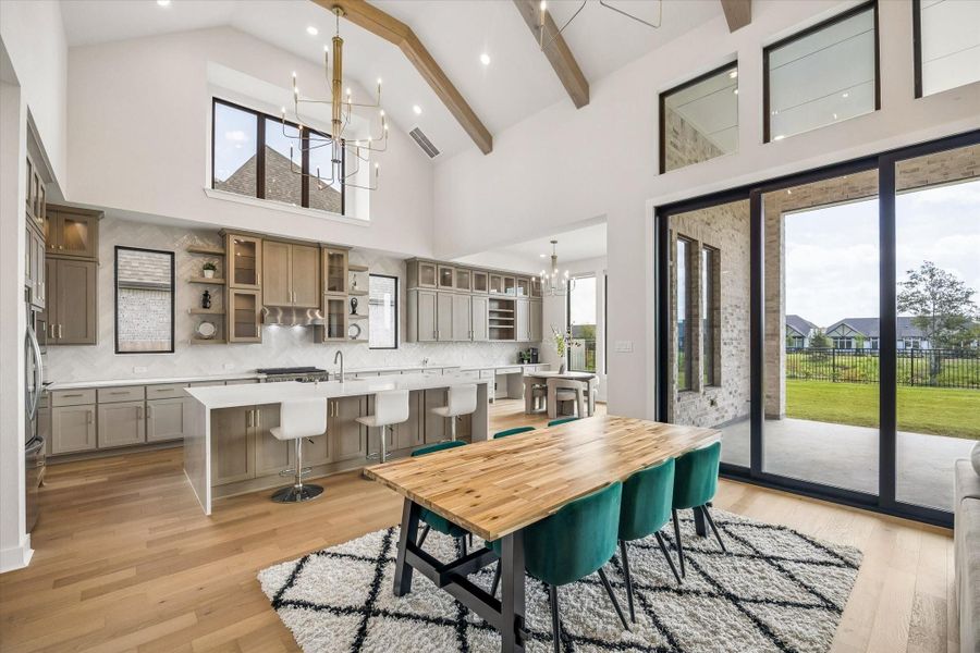 OPEN KITCHEN AND DINING AREA FEATURES SOARING CEILINGS, EXPOSED WOOD BEAMS, OVERSIZED WINDOWS, AND LARGE SLIDING GLASS DOORS OVERLOOKING THE BACKYARD. OPEN KITCHEN AND DINING AREA FEATURES SOARING CEILINGS, EXPOSED WOOD BEAMS, OVERSIZED WINDOWS, AND LARGE SLIDING GLASS DOORS OVERLOOKING THE BACKYARD.