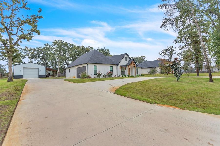 Modern farmhouse with circle driveway, separate metal workshop surrounded by mature trees. Modern farmhouse with circle driveway, separate metal workshop surrounded by mature trees.