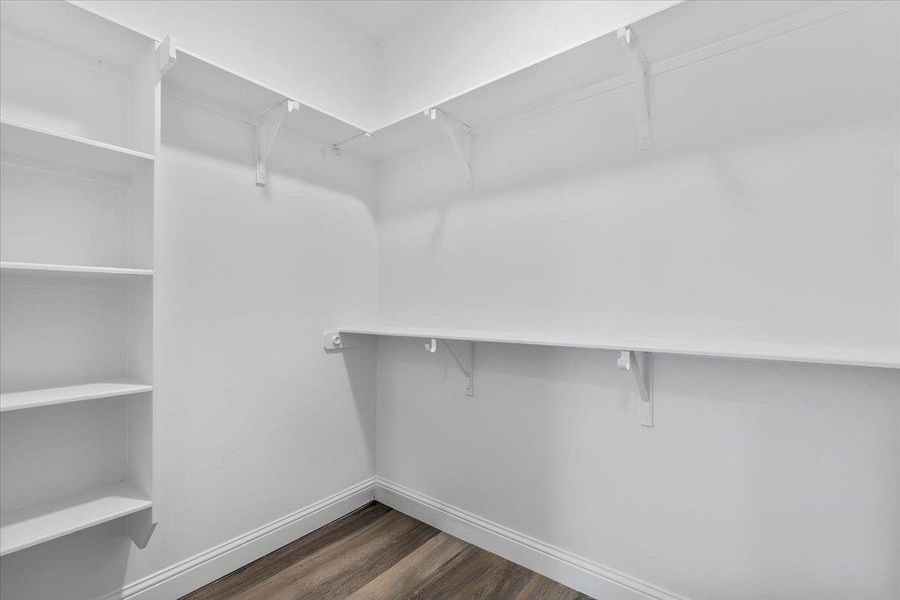 Ample built-in shelving and wood-style flooring maximize storage potential in this walk-in closet. Ample built-in shelving and wood-style flooring maximize storage potential in this walk-in closet.