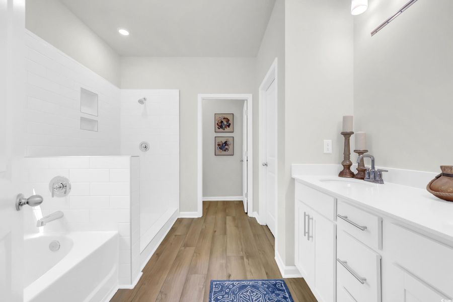 Full bath featuring vanity, a tile shower, a garden tub, and light wood-type flooring Full bath featuring vanity, a tile shower, a garden tub, and light wood-type flooring