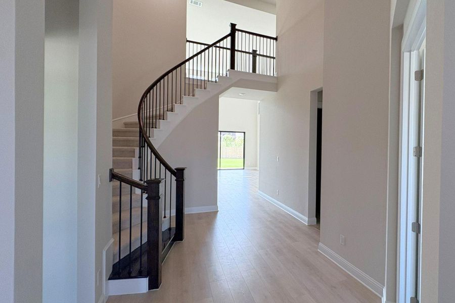 Grand foyer featuring a curved staircase with dark wood newel posts and metal balusters