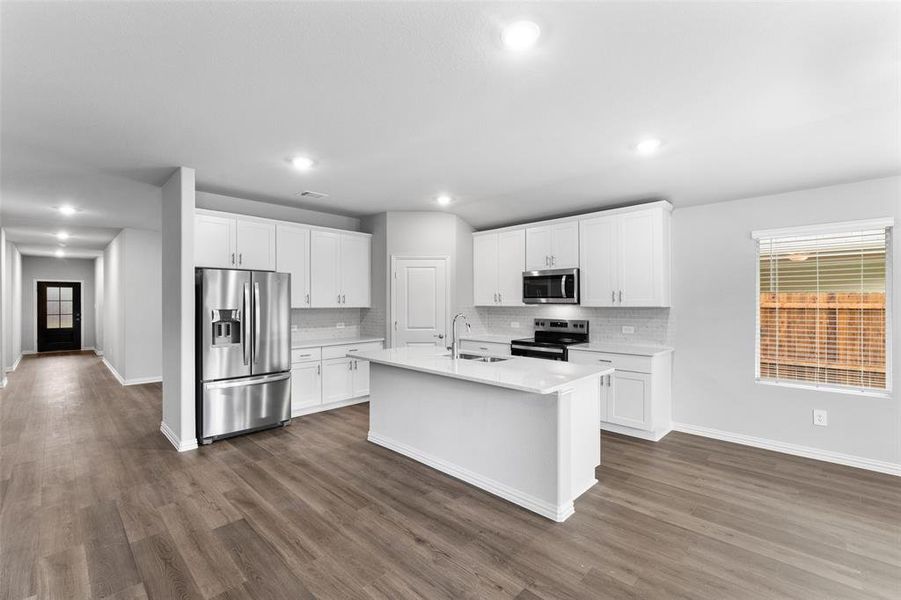 Kitchen featuring appliances with stainless steel finishes, decorative backsplash, light countertops, dark wood finished floors, and recessed lighting Kitchen featuring appliances with stainless steel finishes, decorative backsplash, light countertops, dark wood finished floors, and recessed lighting