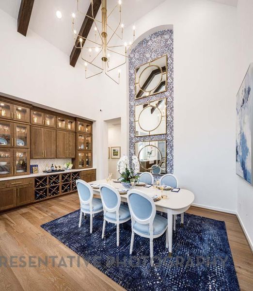 Dining area featuring a high ceiling, a chandelier, light wood-type flooring, and beamed ceiling Dining area featuring a high ceiling, a chandelier, light wood-type flooring, and beamed ceiling
