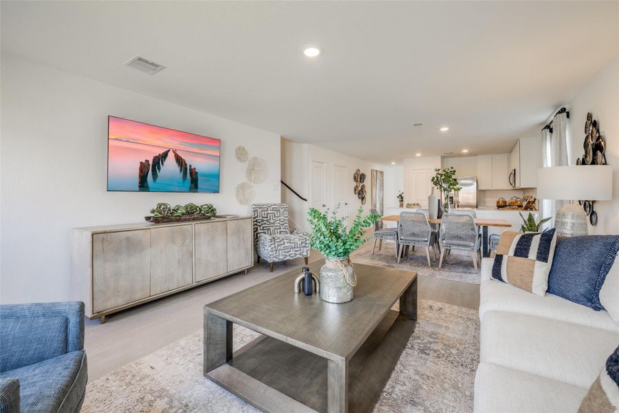 This modern open-concept living space features a cozy seating area with stylish furniture and decor, a sleek kitchen with stainless steel appliances, and a dining area with ample natural light. Perfect for entertaining and comfortable living.