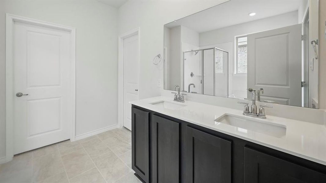 Full bathroom featuring double vanity, a shower stall, and light tile patterned floors