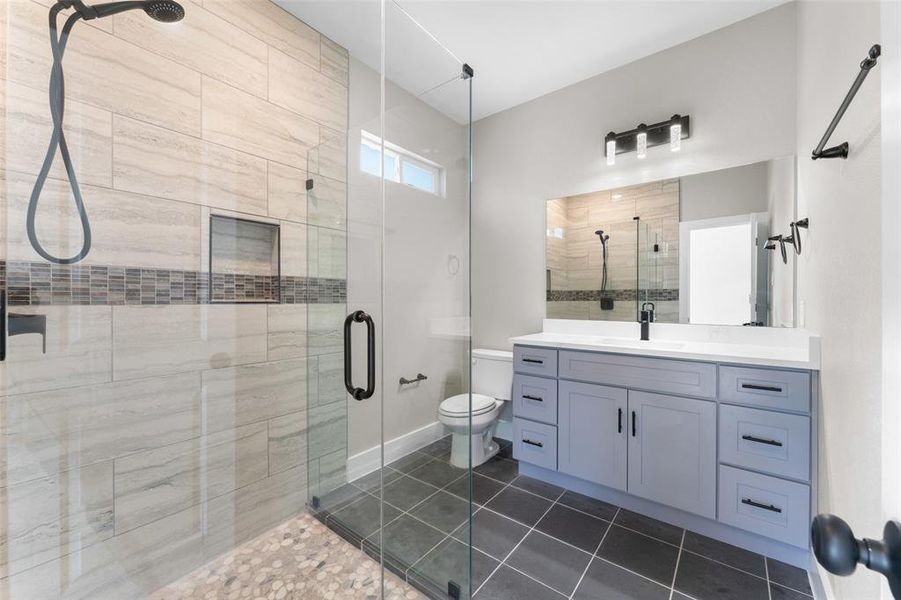 Bathroom with tile patterned floors, vanity, toilet, and a shower with shower door