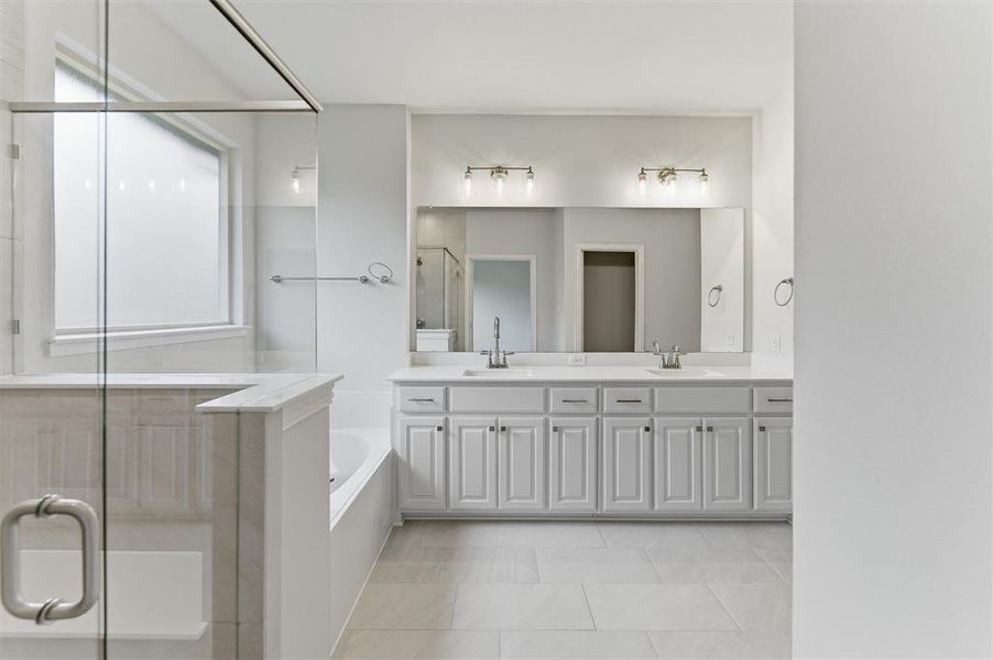 Bathroom featuring a frameless glass shower enclosure, a separate soaking tub, and a double vanity with ample storage