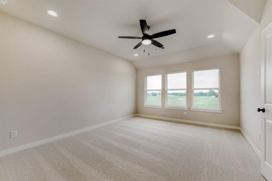 Spacious room featuring three windows, neutral-toned carpeting, a contemporary ceiling fan, recessed lighting, and a paneled door with dark hardware