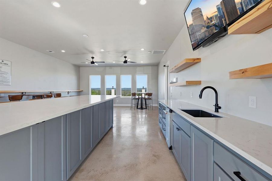 An inviting community space with a large island and ample seating features a practical sink and beverage fridge.