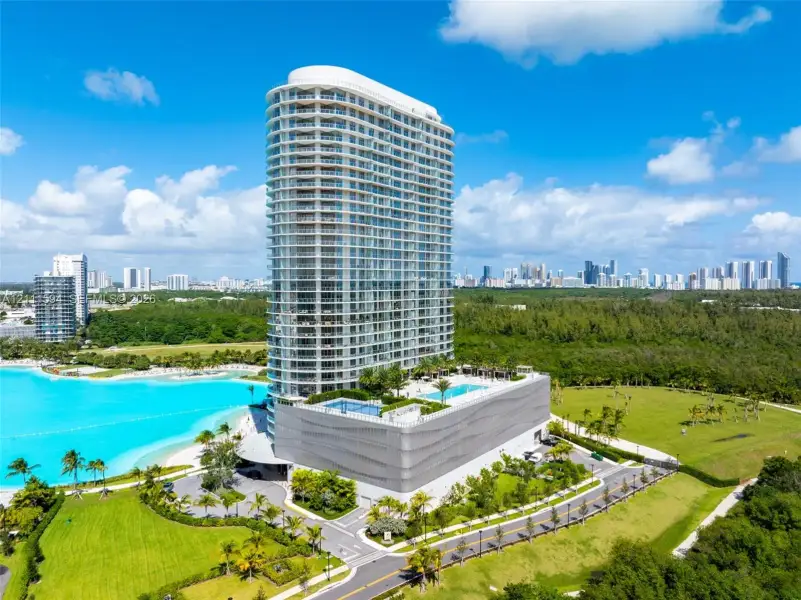 High-rise building featuring a glass facade, multiple wraparound balconies, an elevated swimming pool, and curated landscape grounds High-rise building featuring a glass facade, multiple wraparound balconies, an elevated swimming pool, and curated landscape grounds