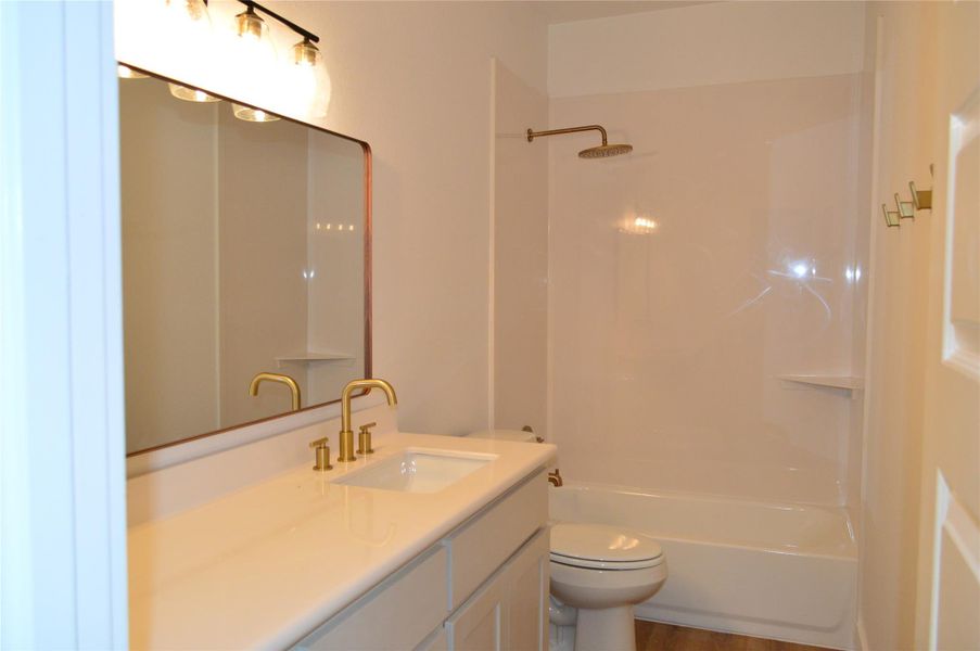 Full bathroom featuring vanity, shower / bath combination, and wood finished floors Full bathroom featuring vanity, shower / bath combination, and wood finished floors