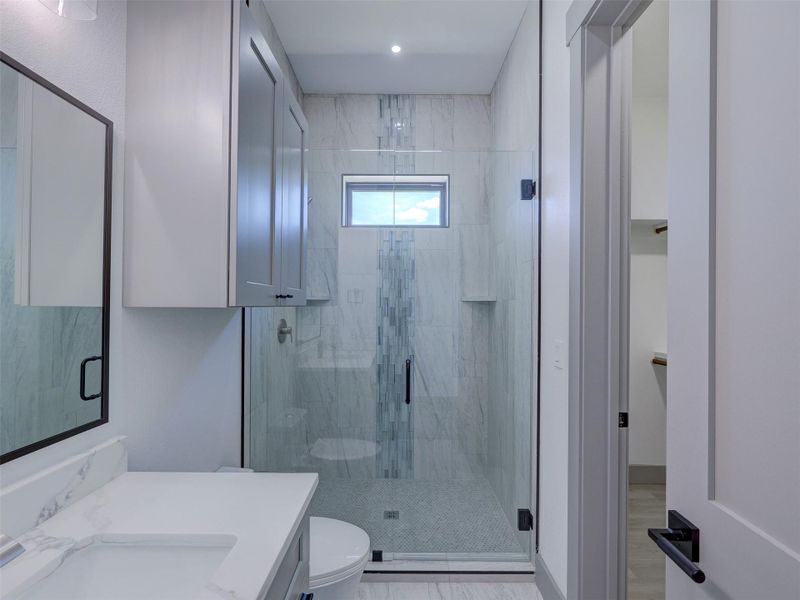 Clean lines and a custom tiled glass shower define this modern bathroom space.