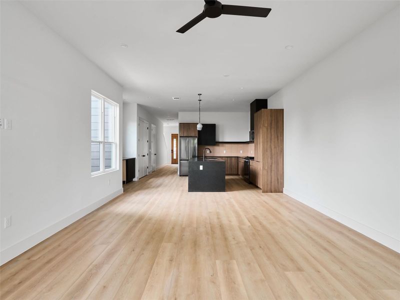 Kitchen with open floor plan, an island with sink, decorative light fixtures, freestanding refrigerator, and a ceiling fan Kitchen with open floor plan, an island with sink, decorative light fixtures, freestanding refrigerator, and a ceiling fan