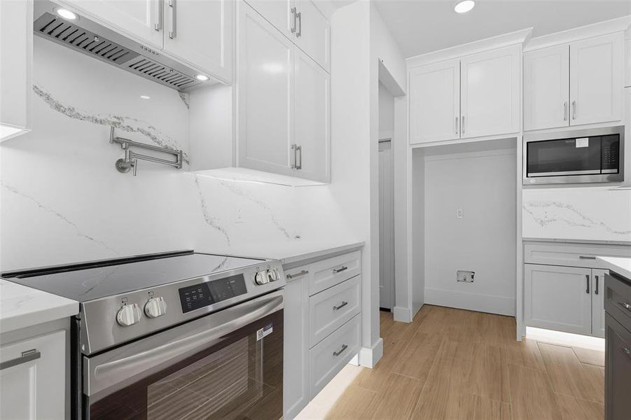 Kitchen with stainless steel appliances, under cabinet range hood, white cabinets, and recessed lighting Kitchen with stainless steel appliances, under cabinet range hood, white cabinets, and recessed lighting