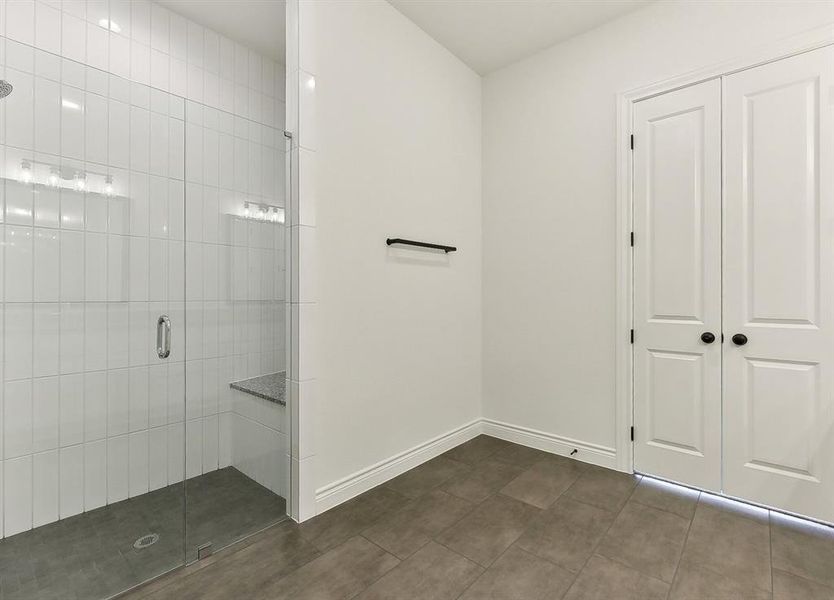 Bathroom featuring a spacious shower with clear glass enclosure, white subway tile walls, and a built-in bench