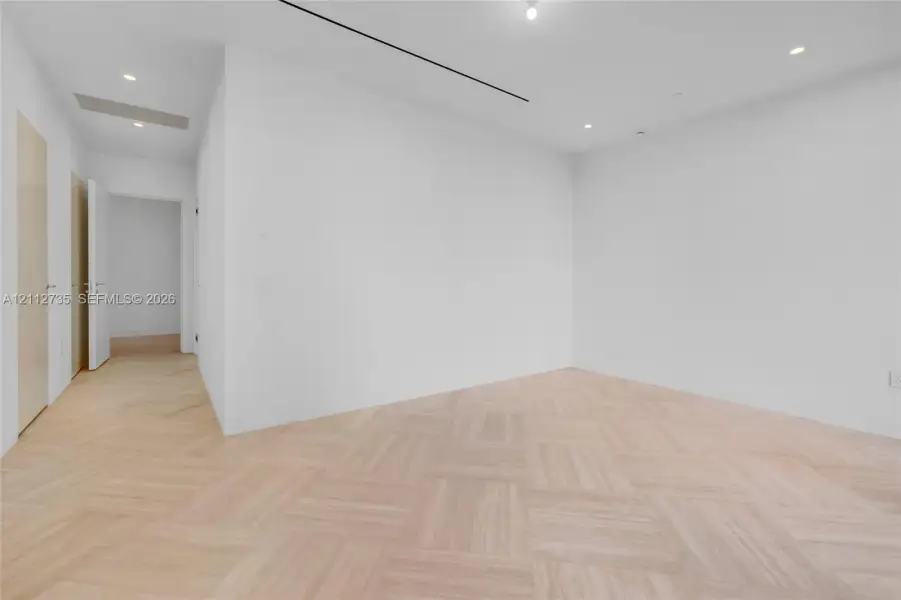 Interior space featuring light-toned wood-finish flooring in a herringbone pattern, recessed lighting, and smooth-finish white walls