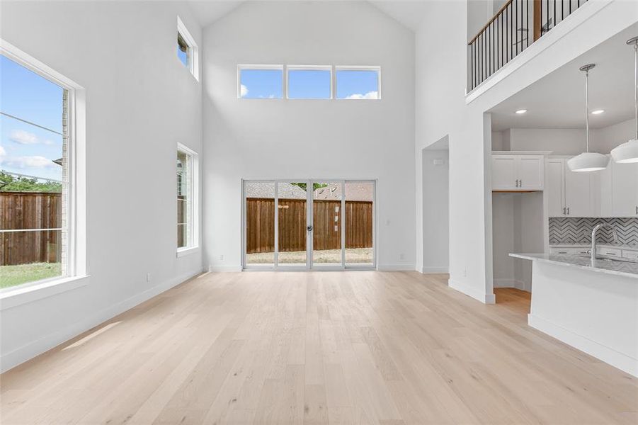 Unfurnished living room with sink, high vaulted ceiling, and light hardwood / wood-style flooring