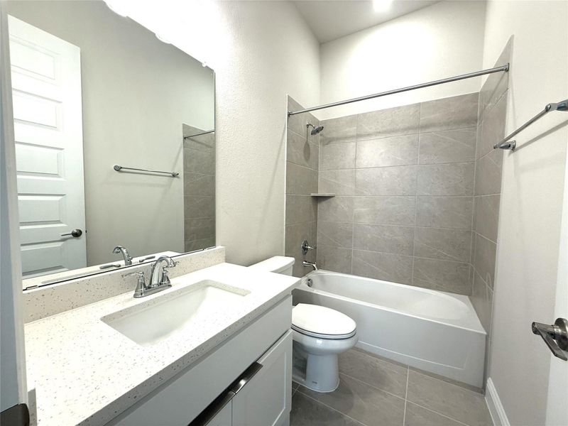 Bathroom featuring shower / washtub combination, vanity, and dark tile patterned floors