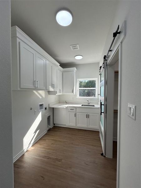 Laundry room with white cabinetry, a barn door, sink, and light stone countertops