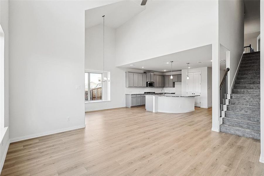 Unfurnished living room with a high ceiling, light wood-style floors, and recessed lighting Unfurnished living room with a high ceiling, light wood-style floors, and recessed lighting