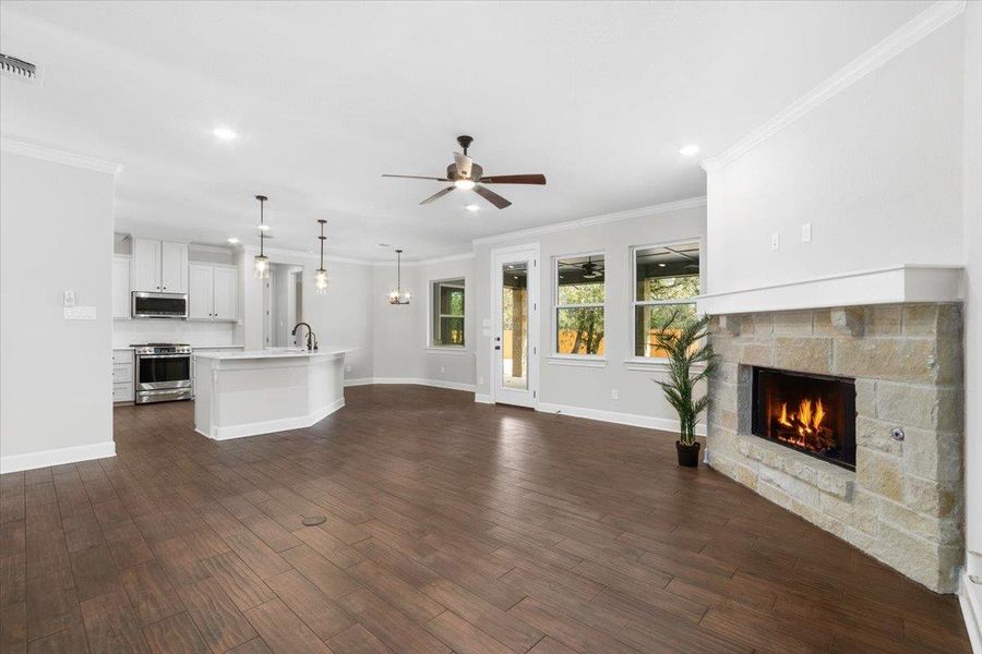 Unfurnished living room featuring a sink, a fireplace, a ceiling fan, baseboards, and dark wood-type flooring Unfurnished living room featuring a sink, a fireplace, a ceiling fan, baseboards, and dark wood-type flooring