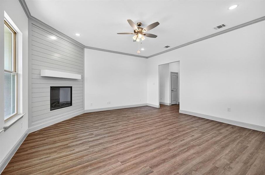 Unfurnished living room featuring crown molding, light wood-style floors, a fireplace, a ceiling fan, and recessed lighting