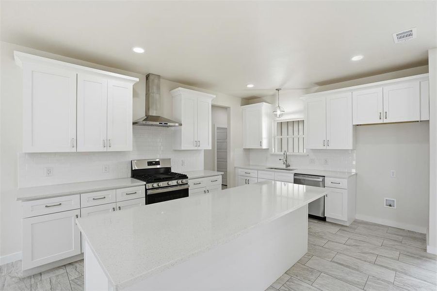 Spacious kitchen featuring an island, white shaker cabinetry, stainless steel appliances, a subway tile backsplash, and light-toned tile flooring