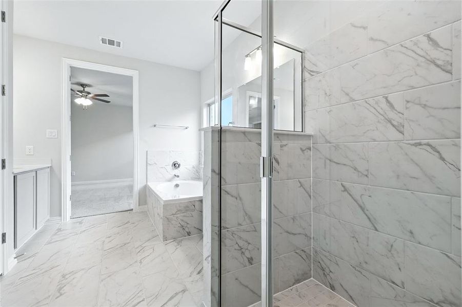 Bathroom featuring marble look tiles, a bath, a ceiling fan, vanity, and a marble finish shower Bathroom featuring marble look tiles, a bath, a ceiling fan, vanity, and a marble finish shower