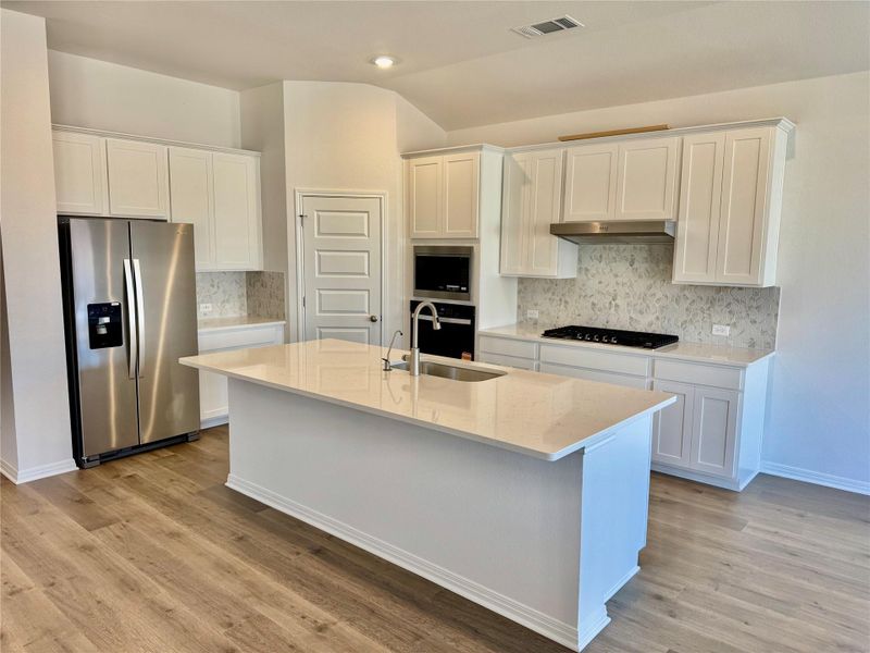 Kitchen featuring backsplash, stainless steel appliances, light stone countertops, white cabinets, and recessed lighting