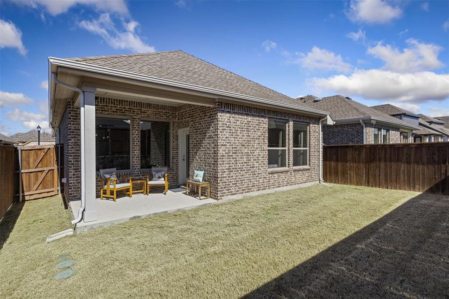 Back of property with a patio, a fenced backyard, brick siding, a yard