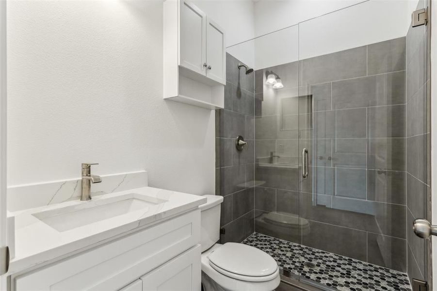 Bathroom with a shower with door, vanity, and toilet