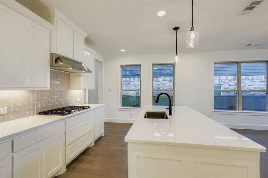 Kitchen with dark wood-style flooring, pendant lighting, recessed lighting, white cabinetry, and tasteful backsplash Kitchen with dark wood-style flooring, pendant lighting, recessed lighting, white cabinetry, and tasteful backsplash