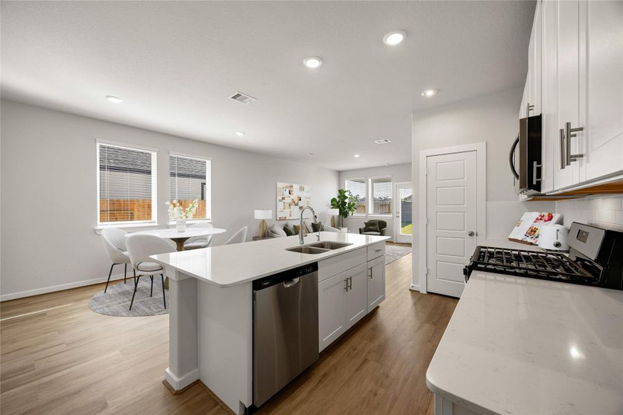 This open kitchen overlooks the dining and living areas, creating the perfect flow for entertaining. Featuring sleek white cabinetry, quartz countertops, stainless steel appliances, and wood-look flooring, this bright space blends modern design with everyday functionality.