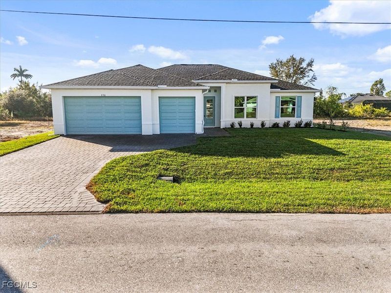 View of front of house with stucco siding, a front yard, decorative driveway, and a garage View of front of house with stucco siding, a front yard, decorative driveway, and a garage