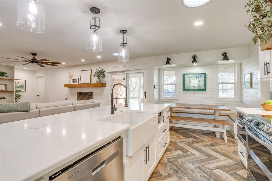 Kitchen featuring stainless steel appliances, open floor plan, pendant lighting, parquet flooring, and white cabinetry