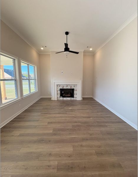 Unfurnished living room featuring dark wood-style floors, a ceiling fan, recessed lighting, a fireplace, and crown molding
