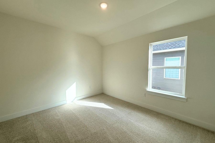 A well-lit bedroom features plush carpeting and a window allowing for ample natural illumination. A well-lit bedroom features plush carpeting and a window allowing for ample natural illumination.