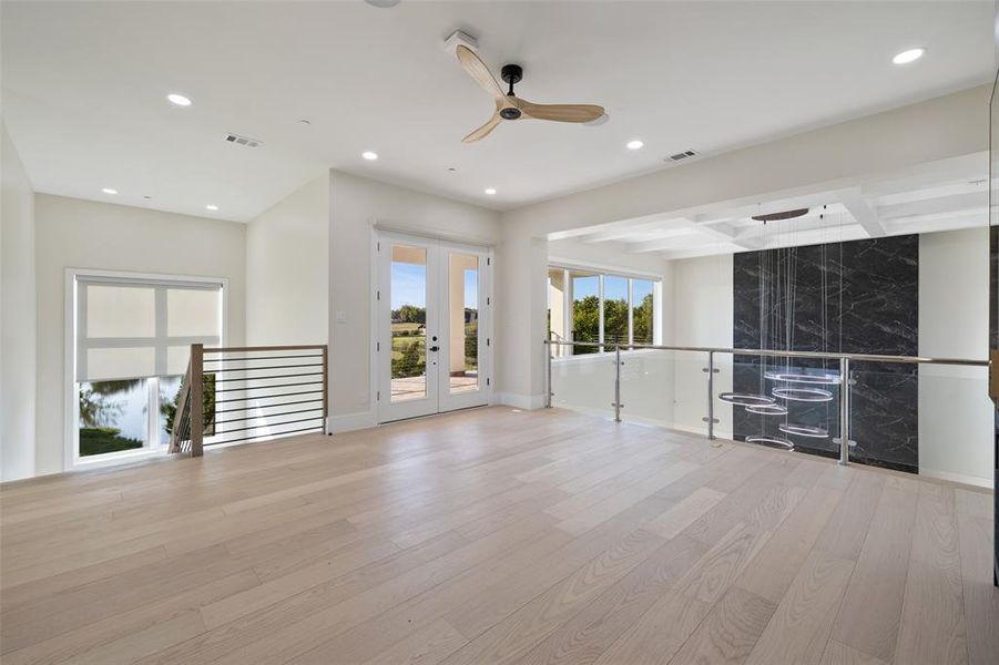 Unfurnished living room with french doors, beamed ceiling, light hardwood / wood-style floors, and ceiling fan