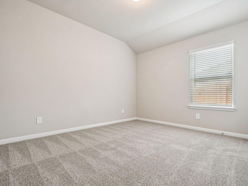 Carpeted spare room featuring vaulted ceiling and baseboards Carpeted spare room featuring vaulted ceiling and baseboards