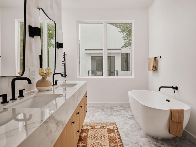 Freestanding soaking tub with wall-mounted matte black fixtures