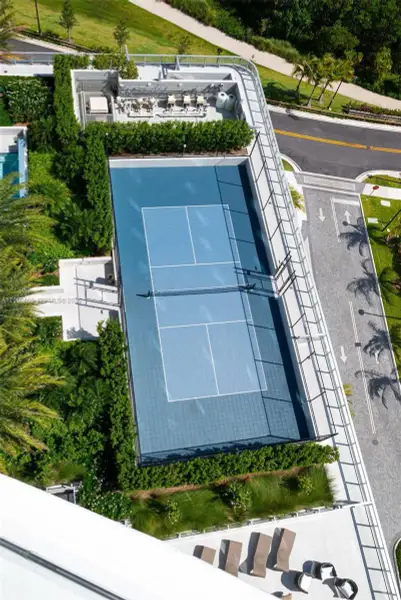 Tennis court featuring a blue hard-surface finish, perimeter fencing, and professional-grade net