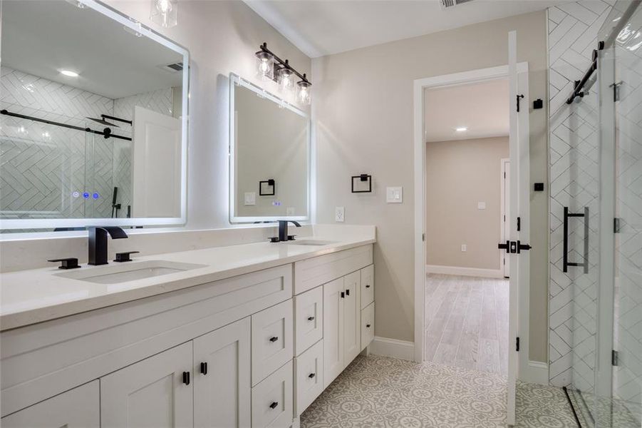 Full bathroom featuring tile patterned flooring, double vanity, a stall shower, and a sink