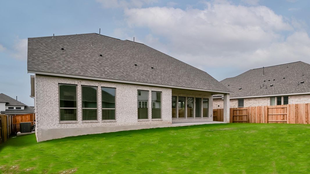Back of property featuring a yard, brick siding, and a fenced backyard
